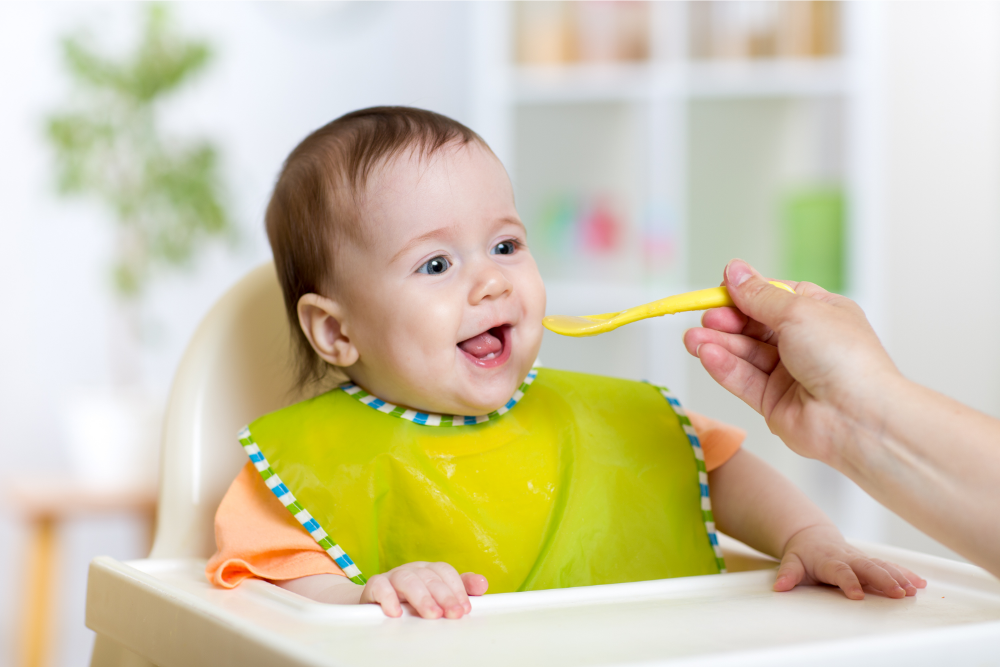 Happy baby eating puree from spouted pouch from RubeeFlex Packaging